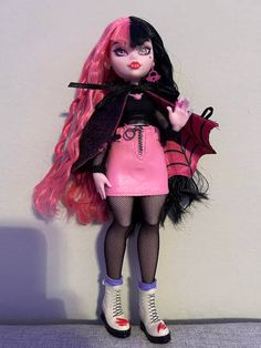 a doll with pink hair and black clothes holding a bat in her hand while standing next to a wall