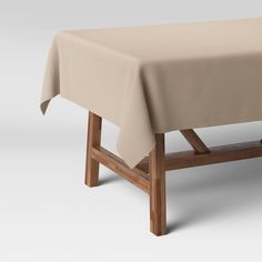 a wooden bench with a beige tablecloth on it