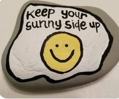 a rock with a smiley face painted on it that says keep your sunny side up