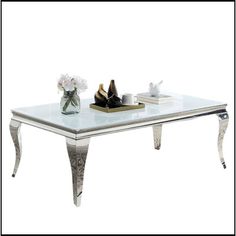 a glass top coffee table with silver trimmings and flowers on the bottom shelf