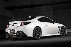 a white sports car is parked in a dark garage with its hood up and lights on