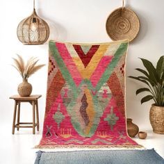 a colorful rug in the corner of a room next to some potted plants and two wicker baskets