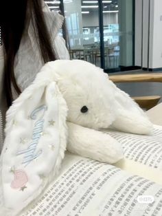 a white stuffed animal sitting on top of an open book