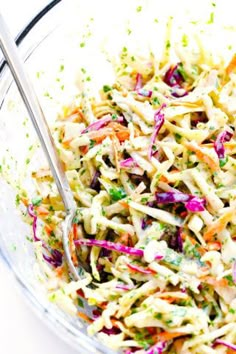 a bowl filled with coleslaw and carrots on top of a white table