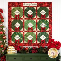 a christmas quilt hanging on the wall next to a green dresser with red poinsettis