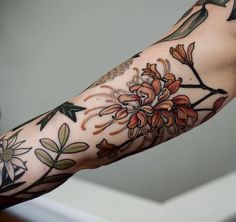 a woman's arm with flowers and leaves on it