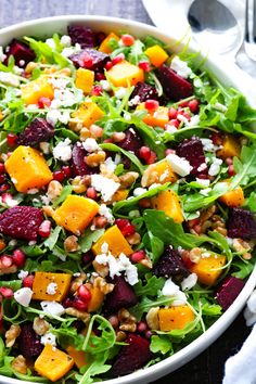 a salad with beets, carrots and feta cheese in a white bowl