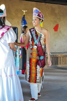 two women dressed in native american clothing standing next to each other