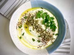 a bowl filled with hummus and garnish on top of a striped napkin