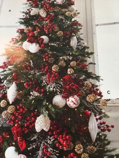 a christmas tree decorated with red and white balls, pine cones, ornaments and bows