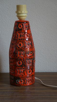 an orange vase sitting on top of a wooden table