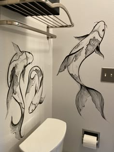 two fish drawn on the wall next to a toilet