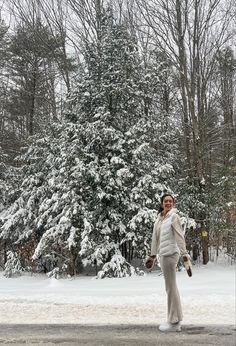 a woman standing in front of a snow covered tree