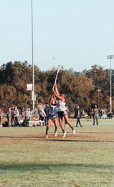 two girls are jumping up to hit a ball with their racquets in the air