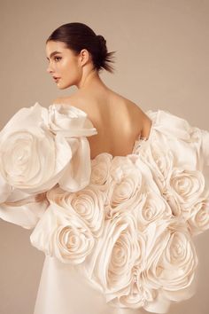 a woman in a white dress with flowers on her shoulders