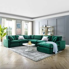 a living room filled with green couches and white pillows on top of a wooden floor