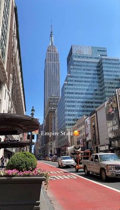 the empire state building towering over new york city is seen in this view from an empty street