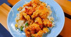 a blue plate topped with chicken and rice on top of a wooden table next to a bench