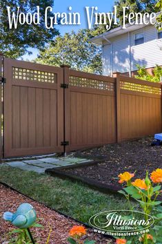 a wooden fence in front of a house with flowers growing on the ground next to it