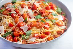 a bowl filled with pasta, tomatoes and parmesan on top of a table