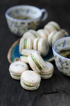 small white and green macaroons on a blue plate next to a tea cup