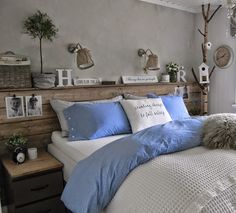 a bed with blue sheets and pillows in a bedroom next to a window, some pictures on the wall