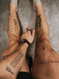 two people with tattoos on their legs and one is holding his hand up to the camera