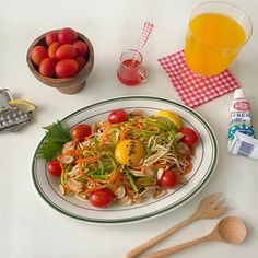 a white plate topped with lots of veggies next to a glass of orange juice