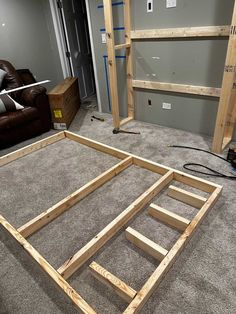 an unfinished bed frame sitting on top of carpeted floor next to a brown couch