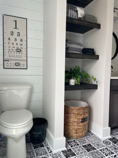 a white toilet sitting in a bathroom next to a shelf filled with towels and other items