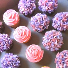 cupcakes with pink and purple frosting in a box