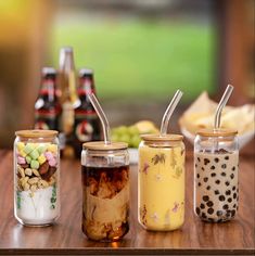 four jars filled with food sitting on top of a wooden table