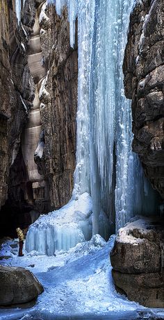 a man standing in front of a frozen waterfall