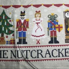 the nutcrackers cross stitched on to a white cloth with red trim