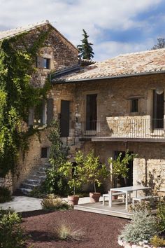 an old stone house with stairs leading up to the upper floor and second story balcony