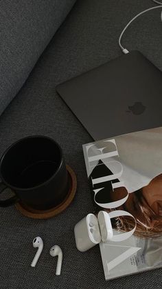 an apple laptop and headphones on the floor next to a magazine with earbuds