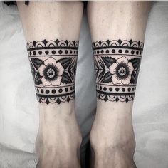 two legs with black and white tattoos on them, one has a flower in the middle