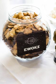 a star wars themed party with snacks and treats in glass jars on a white table cloth