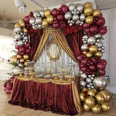 a red and gold balloon arch with silver balloons