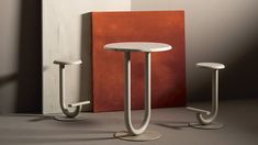 two stools and a table in front of a wall