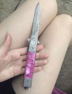 a person holding a pink and silver knife