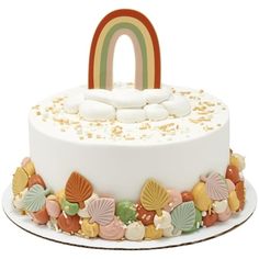 a white cake topped with lots of candy and a rainbow decoration on top of it