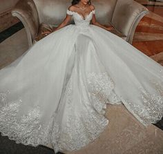 a woman is sitting on a couch in a white wedding dress and posing for the camera