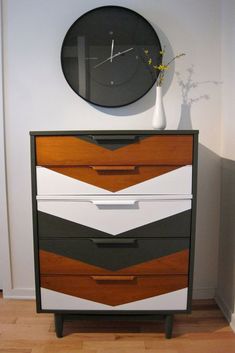 a clock on top of a dresser next to a vase