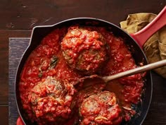 meatballs covered in marinara sauce in a skillet next to a wooden spoon