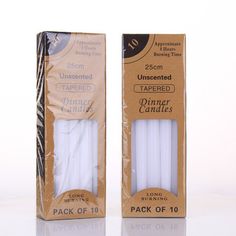 two white candles are in a cardboard box