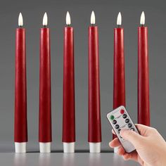 a person is holding a remote control in front of seven red candles with white ones