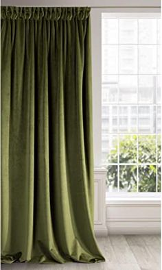 a green curtain hanging in front of a window with white walls and windowsills