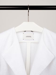 a white shirt is hanging on a black hanger and it has a tag that says,