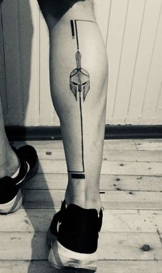 a black and white photo of a person's legs with an arrow tattoo on it